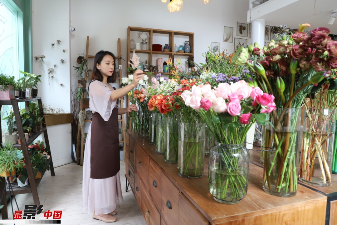 王黎媛是一名河南姑娘，在昆明念完大學后，就再也舍不下春城的藍天陽光、青山碧水，更舍不下這里的四時繁花，于是就干脆留了下來，成了一名媒體人。2017年的時候又毅然辭去工作，創(chuàng)業(yè)開起了花店，成了都市里的一名“花房姑娘”。圖為王黎媛在自己的花店中整理鮮花。新華網(wǎng) 周亞平/攝 念新洪/文